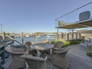 a table and chairs on a deck next to the water at Waterfront Boathouse - Drift Cottage in Plymouth