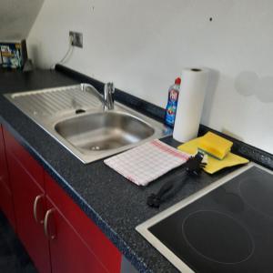 a kitchen counter with a sink and a black counter top at Farbenfrohe Dachgeschoßwohnung in Giesen +18 photos