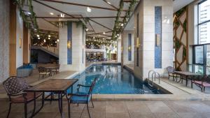 a large swimming pool in a building with tables and chairs at Violet Al Azizia Hotel MASJID Al Qatari in Mecca
