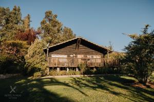 a log cabin with a large deck in a yard at Hotel Fundo Las Tortolas in Limache