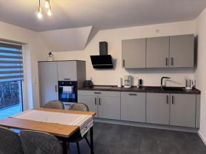 a kitchen with white cabinets and a table with chairs at Ferienwohnung Schöne Aussicht in Hinte