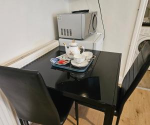 a table with two tea cups and a microwave at Lovely studio flat in Reading