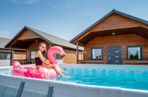 a woman sitting on a pink flamingo in a swimming pool at Domki Agnes in Darłowo