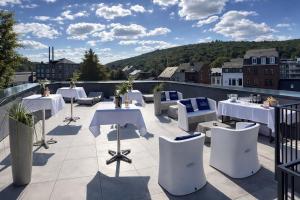 a patio with white tables and chairs on a roof at La Reine Hôtel & Restaurant in Spa