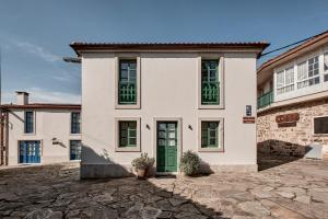 a white house with a green door on a stone driveway at Casa Conde in Furelos