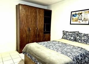 a bedroom with a bed and a wooden cabinet at Pacífico Guest House Recife - Polo Médico e Universidades in Recife