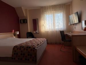 a hotel room with a bed and a desk and a window at Au Relais de l'Ill in Sermersheim
