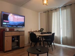 a dining room with a table with chairs and a flat screen tv at Charming T2- apartment in Beauvais in Beauvais