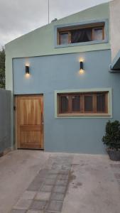 a white building with a wooden door and two windows at Manipa Loft 2 in Cafayate