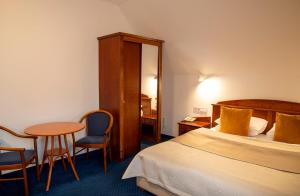 a hotel room with a bed and a table and chairs at Fonte Hotel in Győr