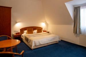 a hotel room with a bed and a table at Fonte Hotel in Győr