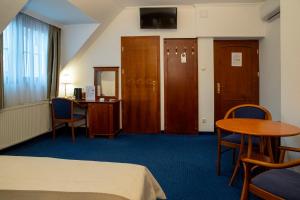 a hotel room with a bed and a table and a desk at Fonte Hotel in Győr