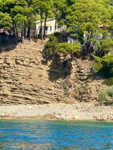 a house on the side of a rocky hill with trees at Ripea Suites - Sul Mare in Montecorice