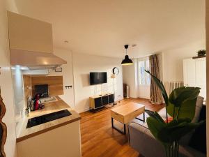 a kitchen and living room with a couch and a table at Le Clemenceau - Appartements meublés in Gien