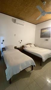 two beds in a room with a ceiling fan at Rumah Saga in Gili Trawangan