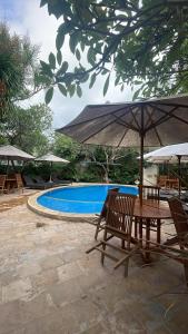 a table and chairs with umbrellas next to a pool at Rumah Saga in Gili Trawangan