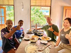 a group of people sitting around a table eating food at Farmhouse Homestay in Negombo