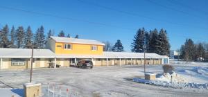 a large yellow building with a snow covered parking lot at Neepawa Motel in Neepawa +22 photos