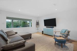 a living room with a couch and a tv at Private Cedar Sauna Retreat - Kitchenette, King Bed, Spa Bath - Deep Cove in North Vancouver