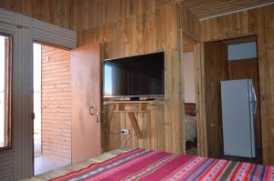 a bedroom with a wall with a flat screen tv at Cabaña Laynaturi in San Pedro de Atacama