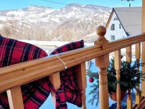 a porch with plaid pillows and a snow covered mountain at Carpathia Magic -adults only in Peştera