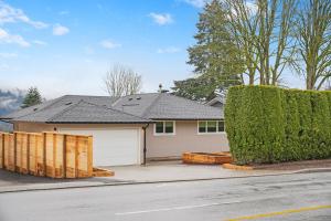 a house with a white garage and a hedge at Private Cedar Sauna Retreat - Kitchenette, King Bed, Spa Bath - Deep Cove in North Vancouver