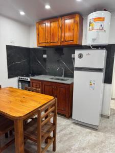 a kitchen with a white refrigerator and a wooden table at VEO Apartamentos in Santa Clara del Mar