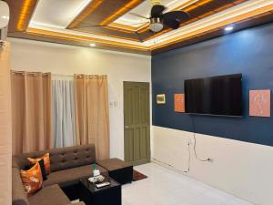 a living room with a couch and a tv on a wall at Sim's Agan South Villas in Lagao III