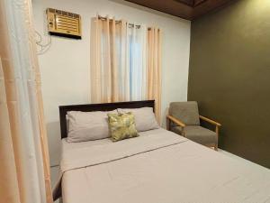 a small bedroom with a bed and a chair at Sim's Agan South Villas in Lagao III