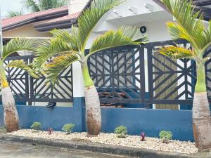 a fence with palm trees in front of a house at Sim's Agan South Villas in Lagao III