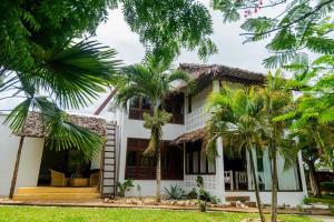 a house with palm trees in front of it at BREEZEACARDEs in Diani Beach