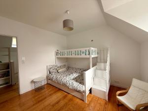 a bedroom with a white bunk bed and a chair at El-Argalora-Bihan in Plobannalec-Lesconil