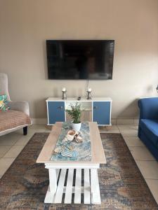 a living room with a table and a tv at Su Casa Port Alfred in Port Alfred
