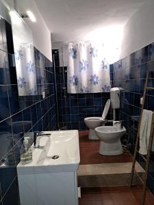 a blue tiled bathroom with a toilet and a sink at Casa Maddalena in Monteriggioni