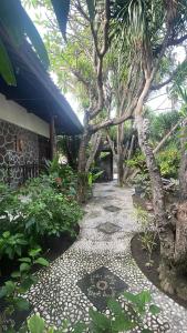 a garden with trees and a stone walk way at Rumah Saga in Gili Trawangan