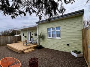 a small green house with a wooden deck at The Cabin at Swelle Cottages in Poundstock
