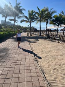 a woman walking down a sidewalk next to the beach at Vidanta World in Jarretadera