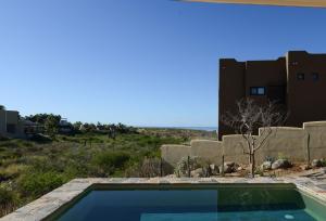 a swimming pool in front of a house with the ocean at Casa Arroyo Pacific in Todos Santos