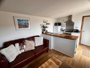 a living room with a couch and a kitchen at The Cabin at Swelle Cottages in Poundstock