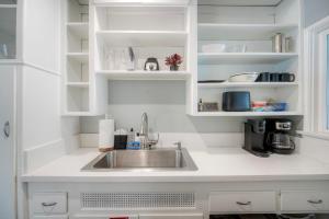 a kitchen with a sink and white cabinets at Oceanfront Condo, Private Balcony, Beach Access, Sunset Views in Carlsbad +21 photos