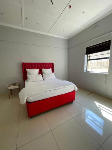 a red bed in a white bedroom with a red headboard at Davidson Lodge in Goodwood +3 photos