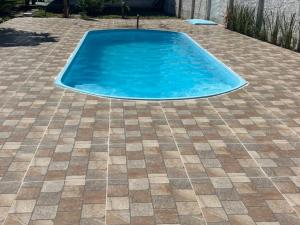 a swimming pool in a yard with a tiled floor at Pousada Bela Rosa in Santa Cruz Cabrália