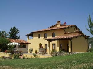ein großes gelbes Haus auf einem Hügel mit einem Hof in der Unterkunft Belvilla by OYO Podere Pulicciano Orciaia in Pian di Scò