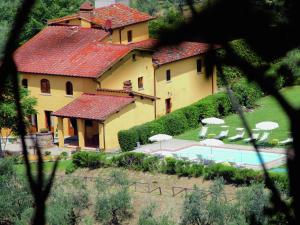 ein großes gelbes Haus mit Pool und Sonnenschirmen in der Unterkunft Belvilla by OYO Podere Pulicciano Orciaia in Pian di Scò