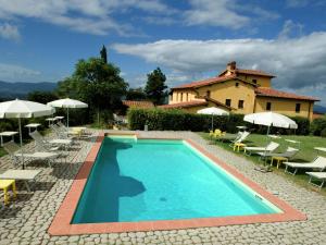 einen Pool vor einem Haus mit Stühlen und Sonnenschirmen in der Unterkunft Belvilla by OYO Podere Pulicciano Orciaia in Pian di Scò