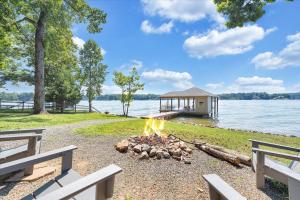 a fire pit in front of a house next to the water at Summer Breeze - Lakefront w/ Private Dock! in Moneta