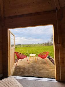 two red chairs and a table on a porch at The Bee Garden - Cosy Cabin in Lede