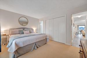 a white bedroom with a bed and a mirror at Lake Vibes - Pet Friendly Lakefront Condo! in Moneta