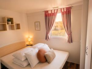 a bedroom with a bed with pillows and a window at Mobile Homes Peroš in Zaton +28 photos
