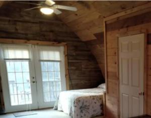 a bedroom with a ceiling fan and two windows at Chalet Cabin 7-Acres Pond! in Andover